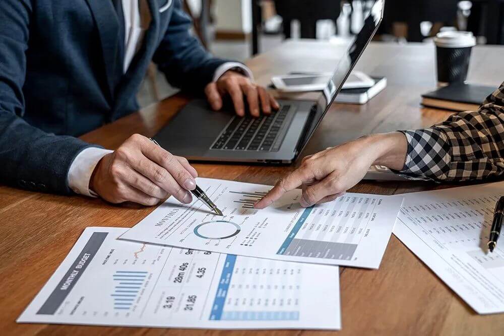 People pointing to a chart on a desk